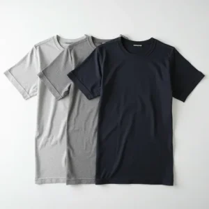 Close-up flat lay of white and charcoal plain cotton T-shirts showing fine knit texture and ribbed neckband — premium cotton manufacturer Tiruppur.